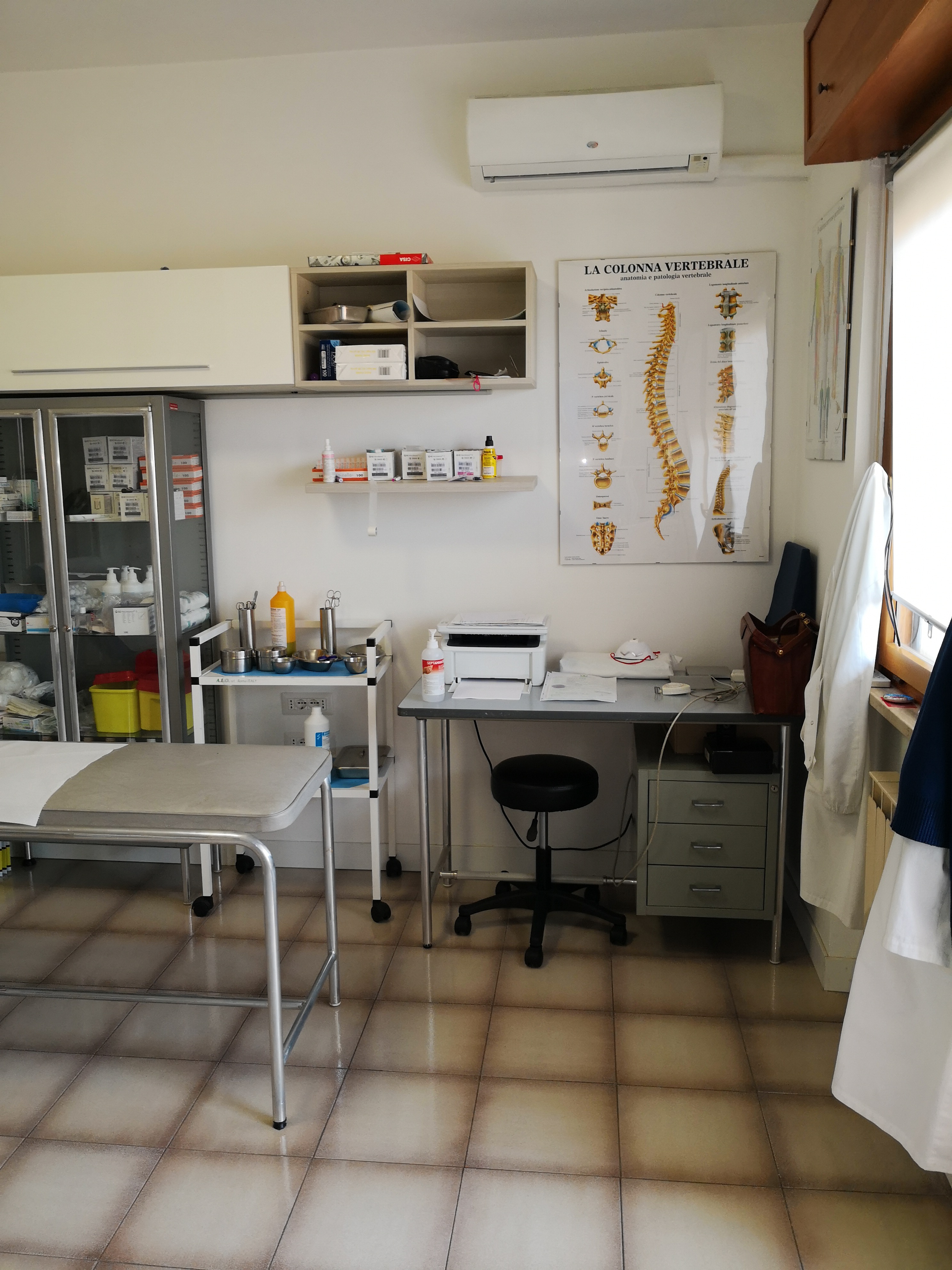 Ambiente visite dello studio con scrivania e tavola anatomica della colonna vertebrale, Roma Torrino