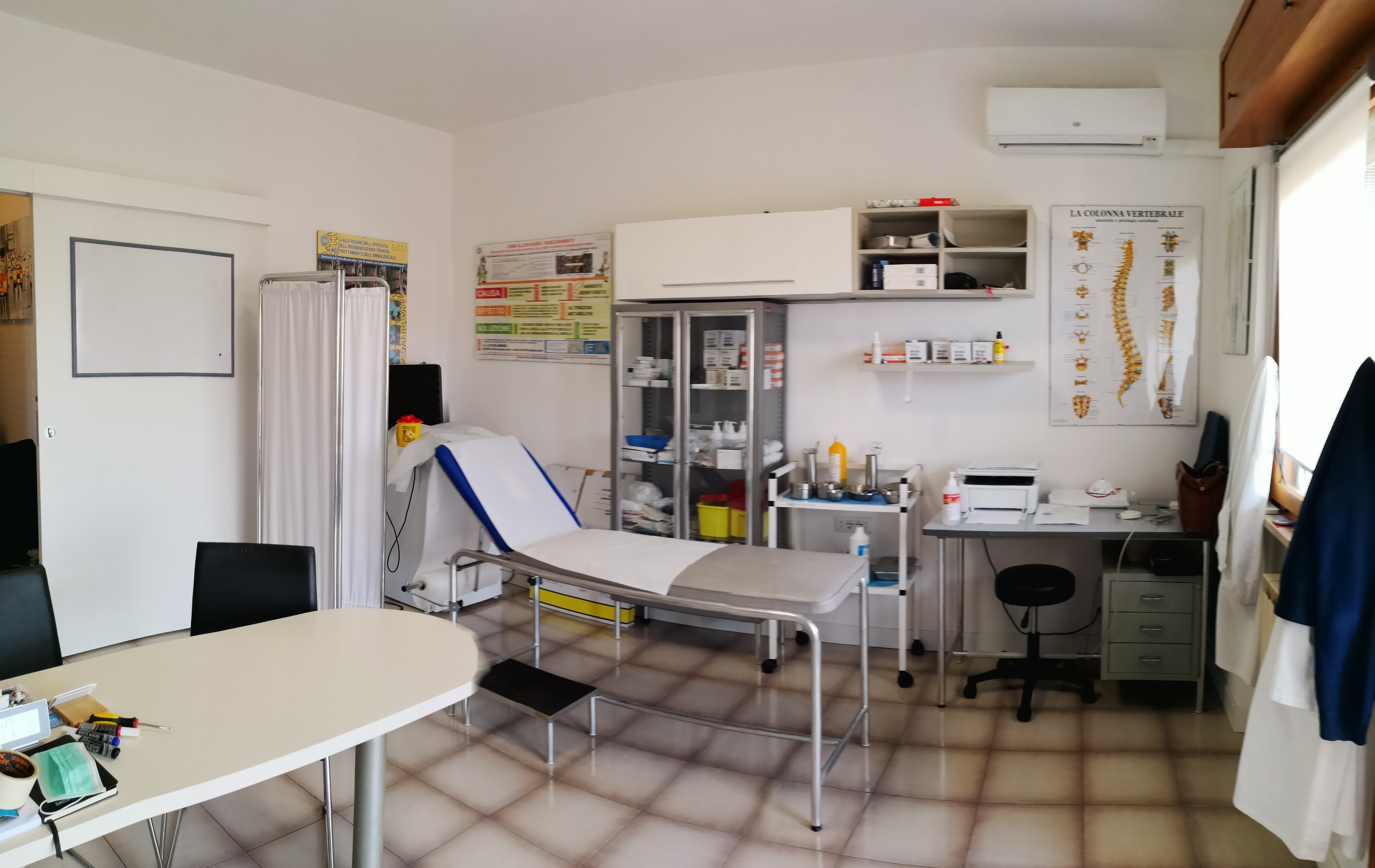 Sala trattamenti dello studio con lettino, paravento e armadio medicale, ozonoterapia a Roma EUR Torrino